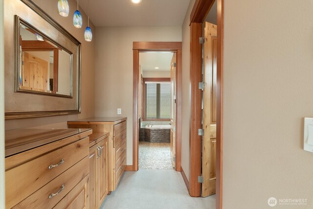 hall featuring light colored carpet and baseboards