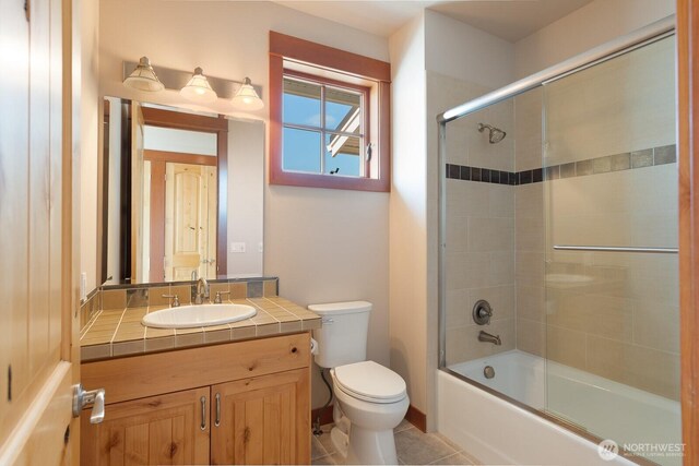 bathroom with toilet, vanity, enclosed tub / shower combo, and tile patterned flooring