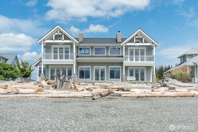 view of front of home with a balcony, a chimney, french doors, and metal roof