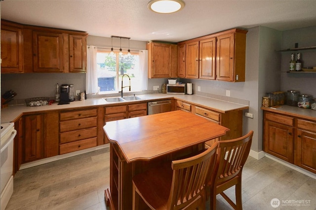 20005 Carper Rd SW, Rochester, WA 98579 - kitchen with a sink, stainless steel appliances, brown cabinetry, light countertops, and decorative light fixtures