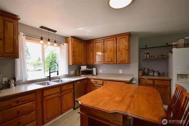 20005 Carper Rd SW, Rochester, WA 98579 - kitchen featuring a sink, appliances with stainless steel finishes, brown cabinetry, hanging light fixtures, and light wood-type flooring