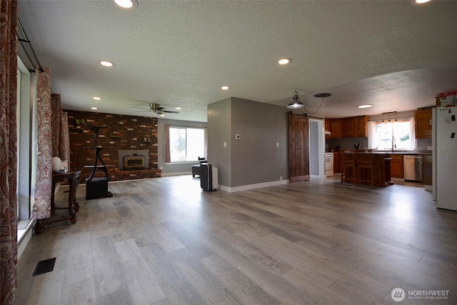 20005 Carper Rd SW, Rochester, WA 98579 - unfurnished living room featuring a textured ceiling, plenty of natural light, light wood-type flooring, a ceiling fan, and recessed lighting