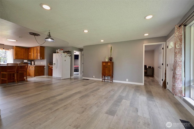 20005 Carper Rd SW, Rochester, WA 98579 - unfurnished living room with a textured ceiling, light wood-style flooring, recessed lighting, baseboards, and a sink