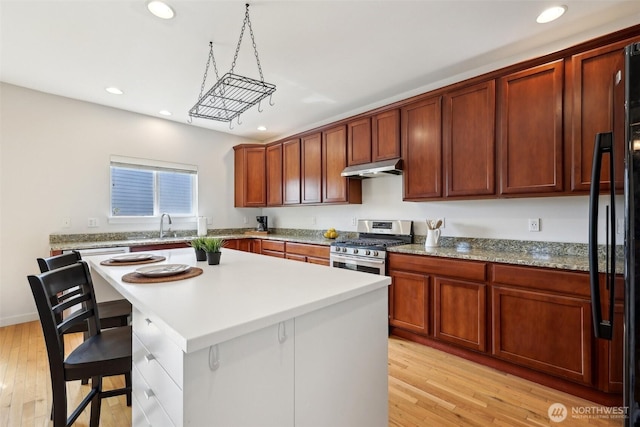27859 256th Ct SE, Maple Valley, WA 98038 - kitchen featuring gas range, recessed lighting, a kitchen breakfast bar, black refrigerator, and light wood-type flooring