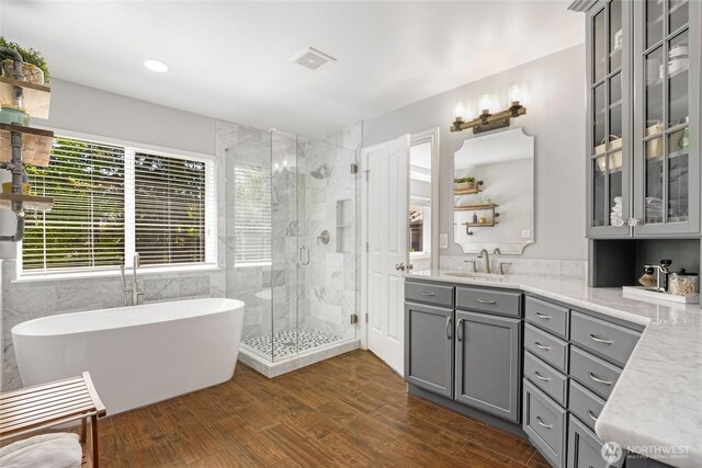 full bathroom with a shower stall, vanity, a freestanding bath, wood finished floors, and recessed lighting