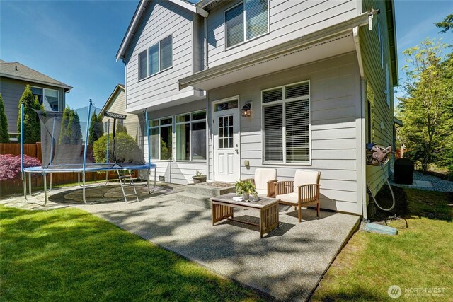 back of house featuring a trampoline, a yard, and a patio