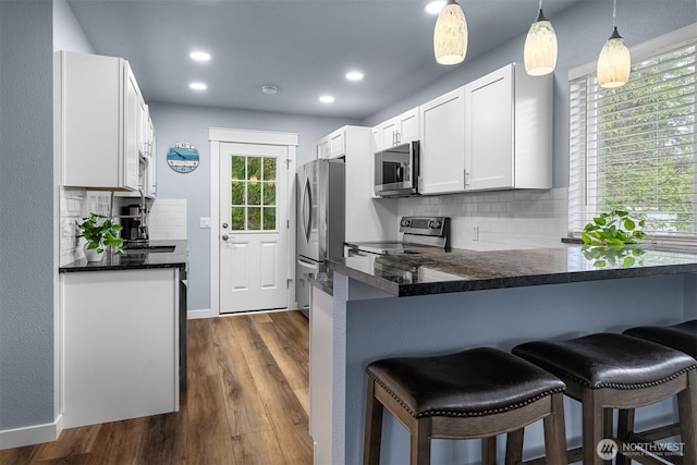 473 Mt Olympus Ave SE, Ocean Shores, WA 98569 - kitchen featuring appliances with stainless steel finishes, a kitchen breakfast bar, white cabinets, decorative backsplash, and a peninsula