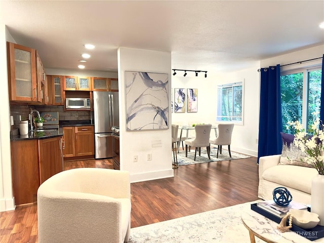 11054 NE 33rd Pl Unit B1, Bellevue, WA 98004 - kitchen with stainless steel appliances, a sink, brown cabinetry, dark wood-style flooring, and dark countertops