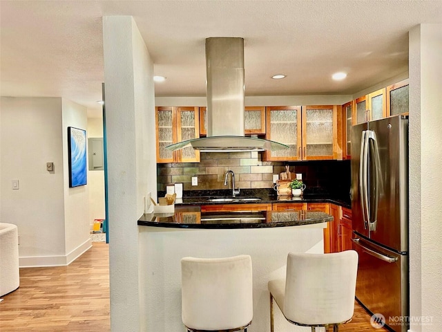 11054 NE 33rd Pl Unit B1, Bellevue, WA 98004 - kitchen with freestanding refrigerator, island range hood, backsplash, a peninsula, and light wood-style floors