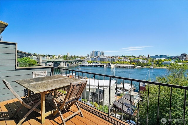balcony with a water view, a view of city, and outdoor dining space