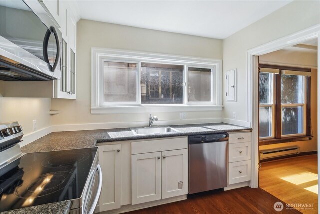 kitchen featuring appliances with stainless steel finishes, a sink, a baseboard heating unit, and white cabinets