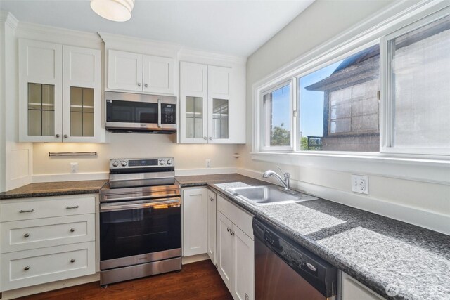 kitchen featuring stainless steel appliances, a sink, white cabinetry, glass insert cabinets, and dark wood-style floors