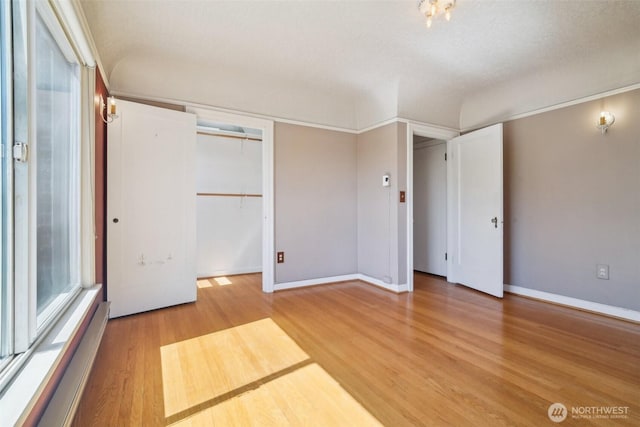 unfurnished bedroom with light wood-style flooring, a baseboard radiator, and baseboards