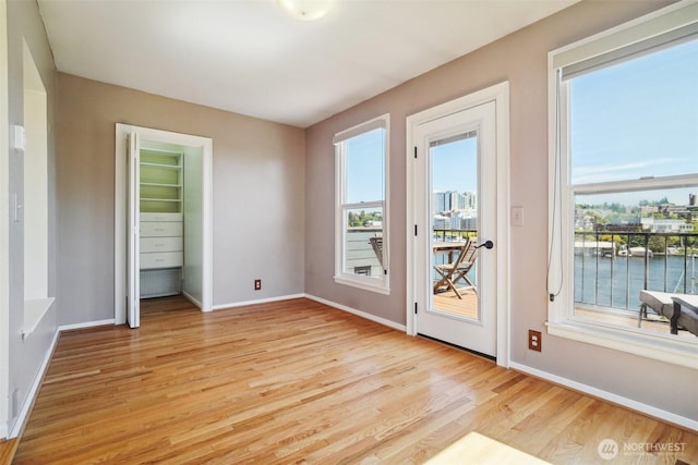 doorway to outside featuring light wood finished floors, baseboards, and a water view