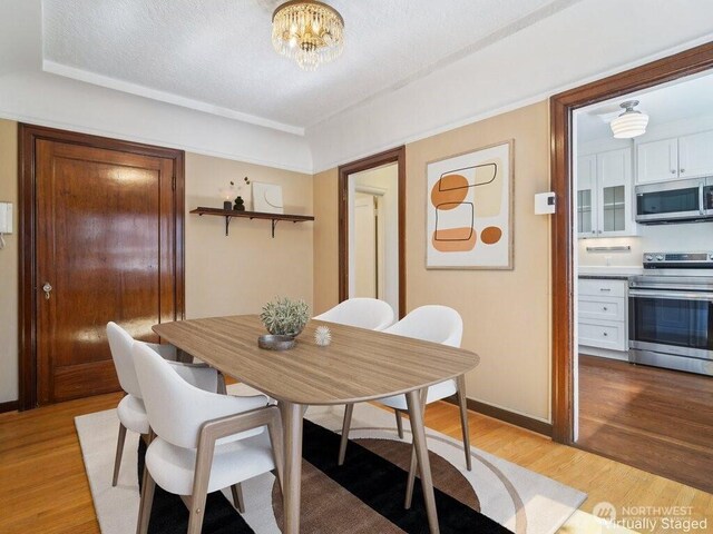 dining area featuring light wood finished floors, a chandelier, and baseboards
