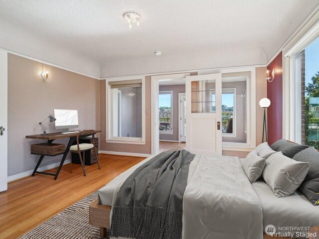 bedroom featuring light wood finished floors, an office area, and baseboards
