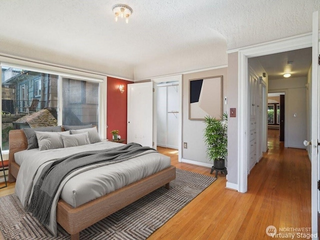 bedroom featuring light wood-style floors, a textured ceiling, and baseboards