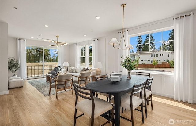 dining area featuring a healthy amount of sunlight, a chandelier, and light wood-type flooring