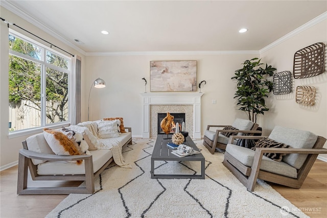 living room featuring light wood-style flooring, a glass covered fireplace, ornamental molding, recessed lighting, and baseboards