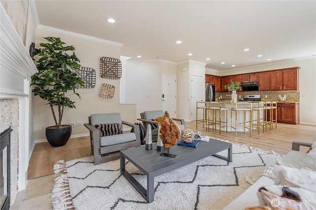 living room featuring recessed lighting, crown molding, light wood finished floors, a fireplace, and baseboards
