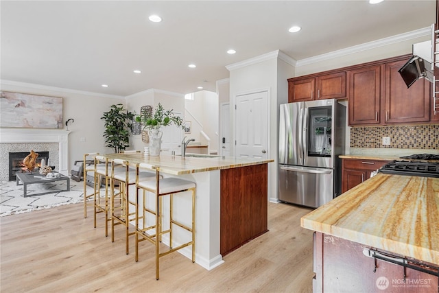 kitchen featuring smart refrigerator, a sink, light wood finished floors, crown molding, and range