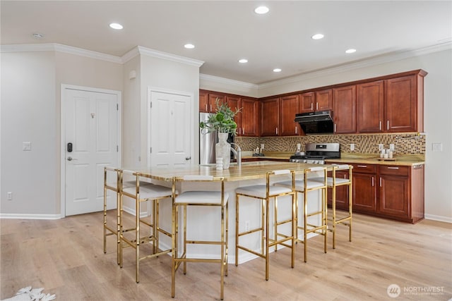 kitchen with stainless steel gas stove, light wood finished floors, tasteful backsplash, light countertops, and recessed lighting