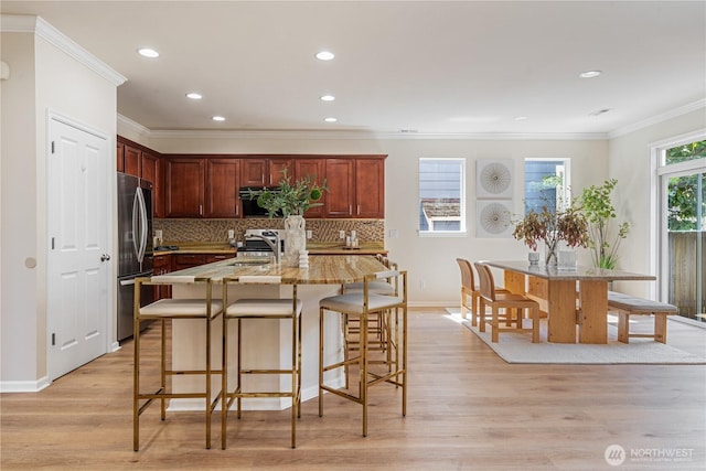 kitchen featuring stainless steel refrigerator, backsplash, light wood-type flooring, recessed lighting, and crown molding