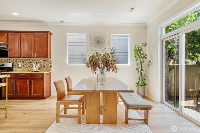 dining area featuring light wood finished floors, ornamental molding, and recessed lighting