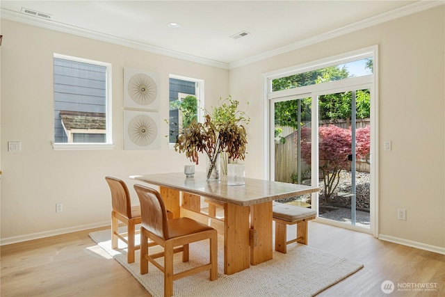dining space featuring light wood-style flooring, baseboards, and crown molding