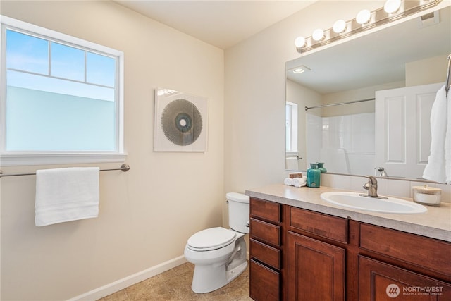 bathroom featuring healthy amount of natural light, baseboards, toilet, and vanity