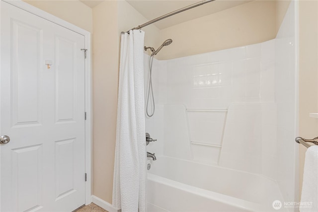 bathroom featuring baseboards and shower / bathtub combination with curtain