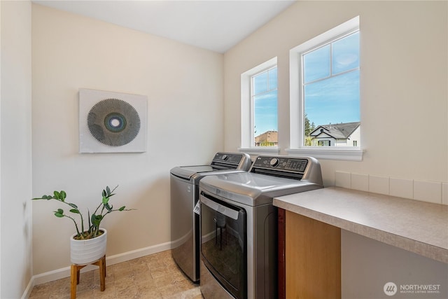 washroom with independent washer and dryer and baseboards