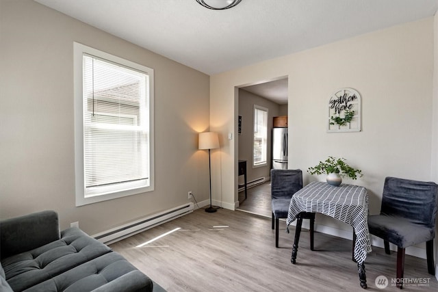 dining space with baseboard heating, light wood-style floors, and baseboards
