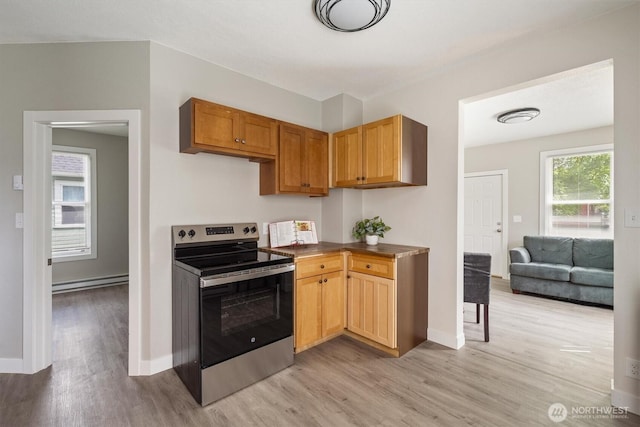 kitchen featuring stainless steel range with electric cooktop, light wood-type flooring, a baseboard radiator, baseboards, and dark countertops