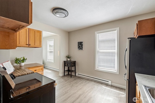 kitchen featuring baseboard heating, freestanding refrigerator, light wood-style flooring, and baseboards