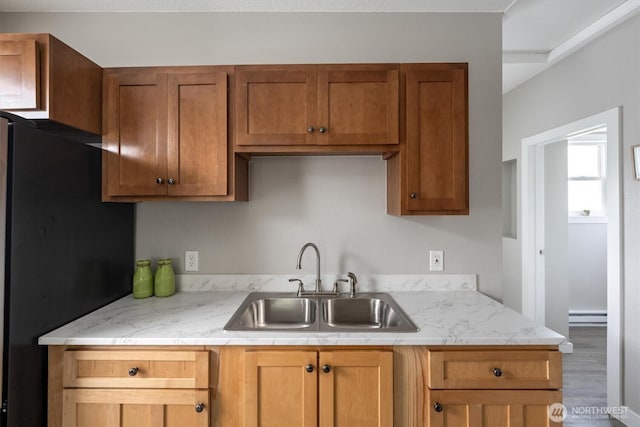 kitchen featuring a sink, light countertops, freestanding refrigerator, and baseboard heating