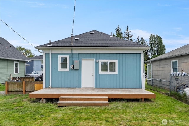 back of house featuring a wooden deck and roof with shingles