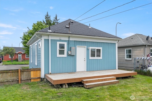 back of property with a deck and roof with shingles
