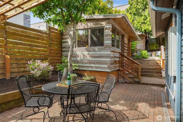 view of patio with fence, outdoor dining space, and stairway