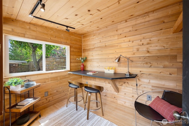bar featuring rail lighting, wood ceiling, wooden walls, and wood finished floors