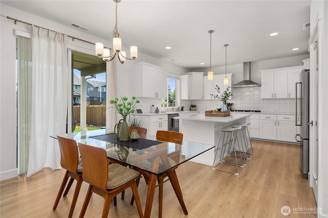 dining area with light wood-style floors, a chandelier, and recessed lighting