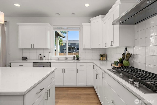 kitchen with under cabinet range hood, appliances with stainless steel finishes, a sink, white cabinets, and recessed lighting