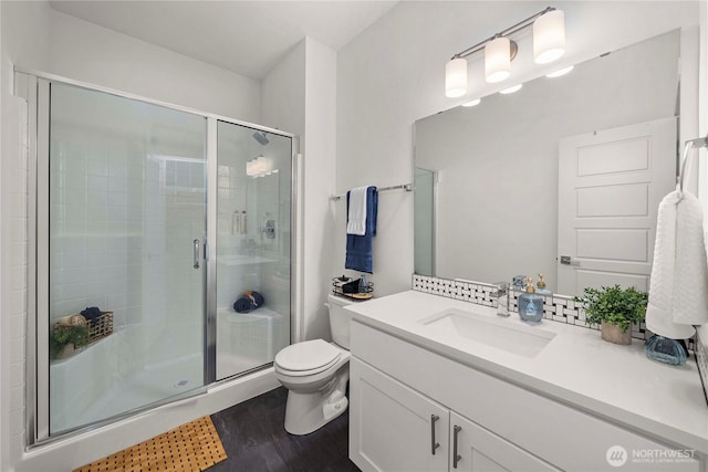 bathroom featuring a stall shower, wood finished floors, toilet, and vanity