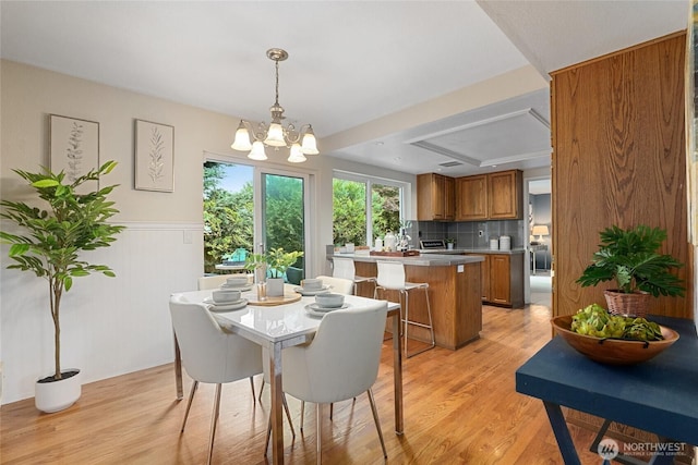 707 Harvest Rd, Bothell, WA 98012 - dining room with light wood finished floors, a chandelier, and a wainscoted wall