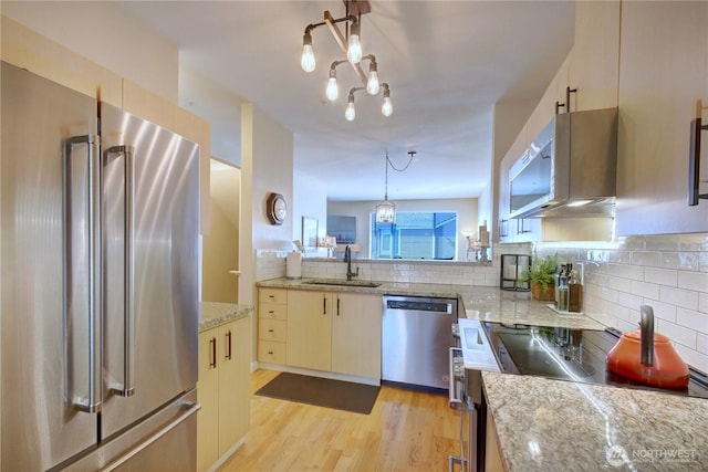 14721 1st Ln NE Unit 102, Duvall, WA 98019 - kitchen featuring stainless steel appliances, a sink, a chandelier, decorative backsplash, and light wood-style floors