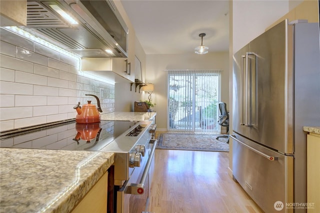 14721 1st Ln NE Unit 102, Duvall, WA 98019 - kitchen with appliances with stainless steel finishes, wall chimney exhaust hood, tasteful backsplash, and light wood-type flooring