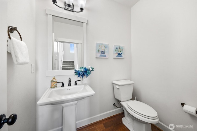 half bathroom with toilet, baseboards, and wood finished floors