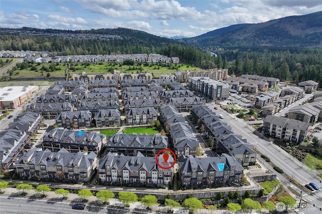 drone / aerial view featuring a residential view, a mountain view, and a view of trees