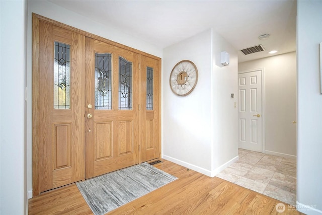 foyer entrance featuring baseboards, light wood-type flooring, and visible vents