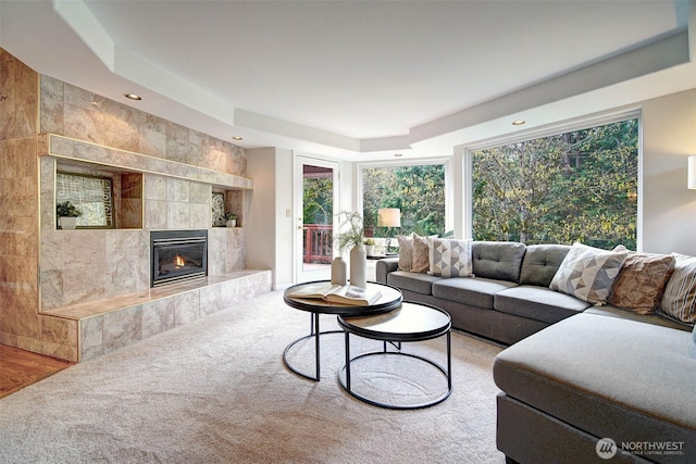 living room featuring a raised ceiling, carpet, a high end fireplace, and recessed lighting